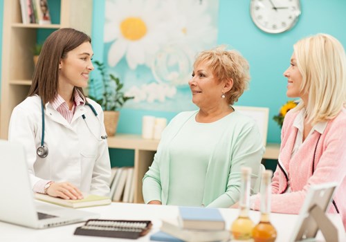 A female doctor talking to an older woman and a younger woman in a floral decorated office